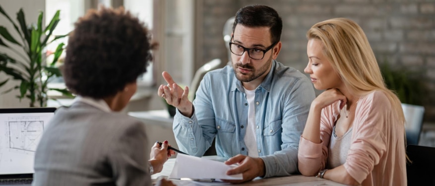 Un homme et une femme discutent avec un couple à une table dans une agence immobilière