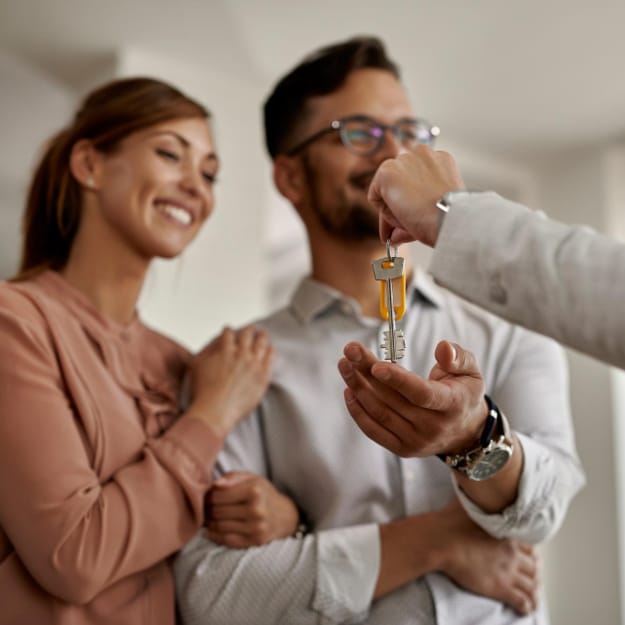 Un homme et une femme tiennent une clé symbolisant l'accès à leur nouvelle maison